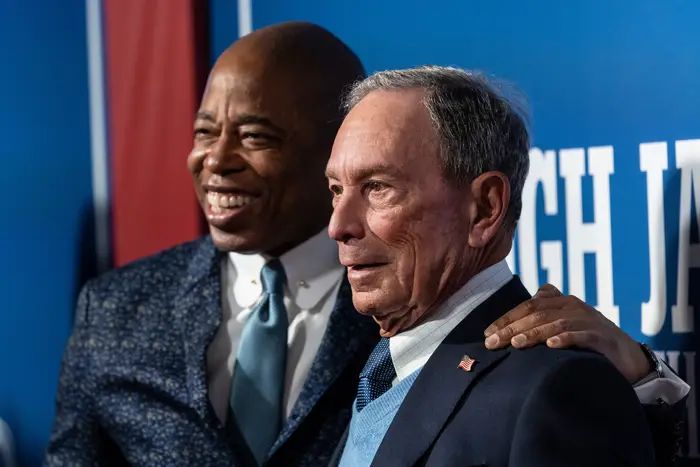 Mayor Eric Adams and former Mayor Michael Bloomberg smile at an event.